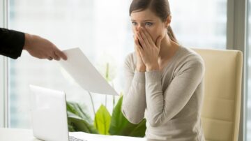 Young woman shocked when receiving dismissal notification from boss. Upset female employee worrying because of mistakes in calculations. Office worker can not believe in breaking employment contract